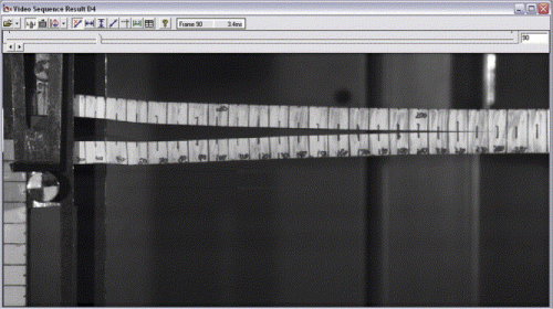 This is a still frame from a high speed video sequence of a DCB (double cantilevered beam) test. The adhesive bond between two pieces of composite is being tested by pulling the ends apart (left hand side) at a high rate. The upper grip is fixed, while the lower grip is being pulled down in a drop weight impact tester. High speed video enables measurement of the crack length throughout the test, and hence crack propagation velocity can be measured. The video sequence also allows the direct measurement of the displacement of the lower grip (notice the target and scale on the left hand side). The force in the upper grip is measured and correlated with displacement and crack length measurements.