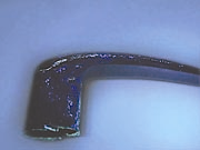 Figure 2b
Figure 2a and 2b: All castings are porous to some extent. With a decorative part such as a door handle, porosity matters more because finish is a selling point. This handle looked fine immediately after polishing (above) but was actually very porous, as revealed here with penetrating florescent dye under ultraviolet light (bottom). If the finishing process had continued, contaminants in these pores would have appeared later, spoiling the part. [Photos courtesy of Aircraft X-ray Laboratories, Inc., Huntington Park, Calif.immediately after polishing (left) but was actually very porous, as revealed here with penetrating florescent dye under ultraviolet light (right). If the finishing process had continued, contaminants in these pores would have appeared later, spoiling the part. [Photos courtesy of Aircraft X-ray Laboratories, Inc., Huntington Park, Calif.